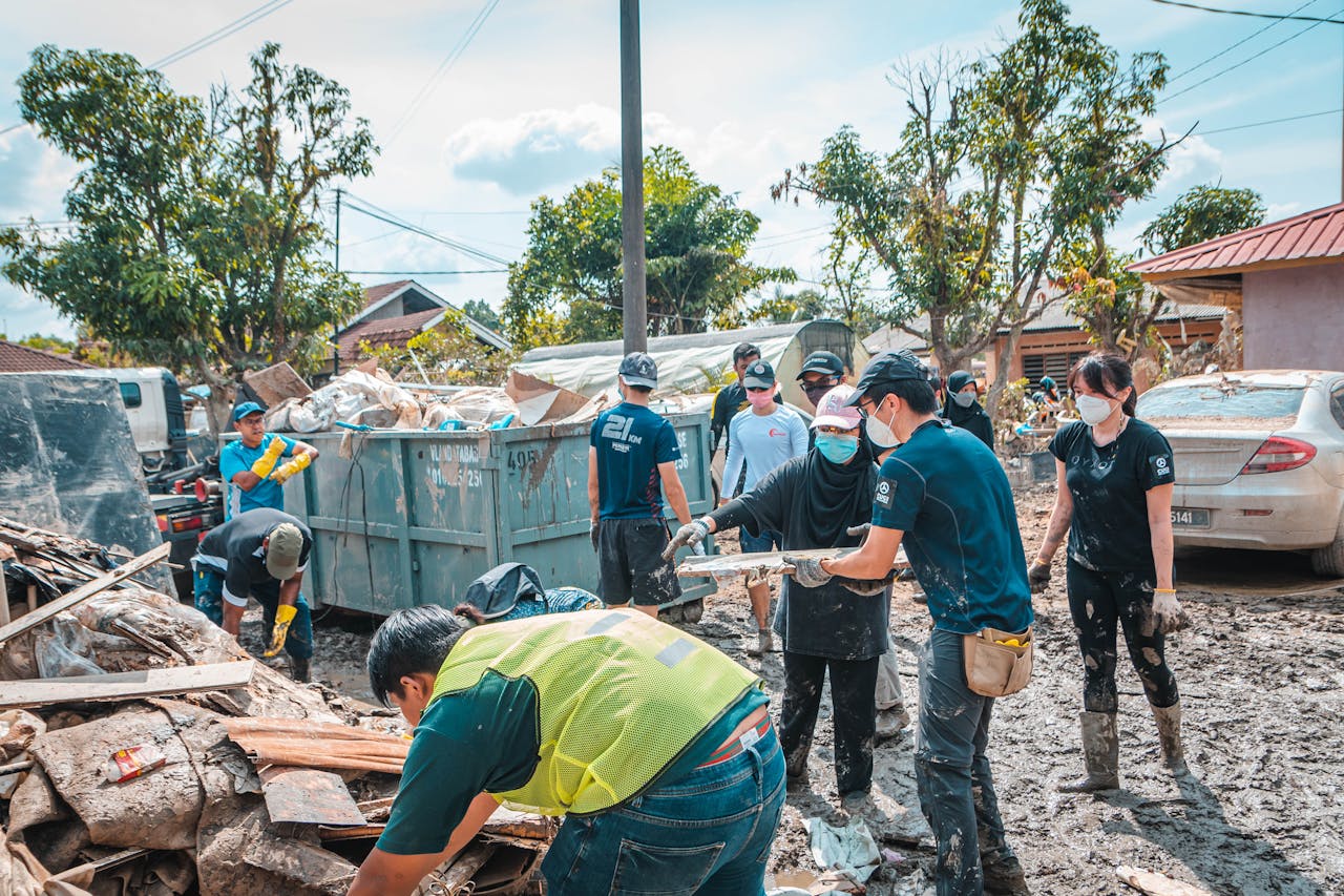 Volunteers work together to clean up debris after a natural disaster, showcasing community effort and teamwork.